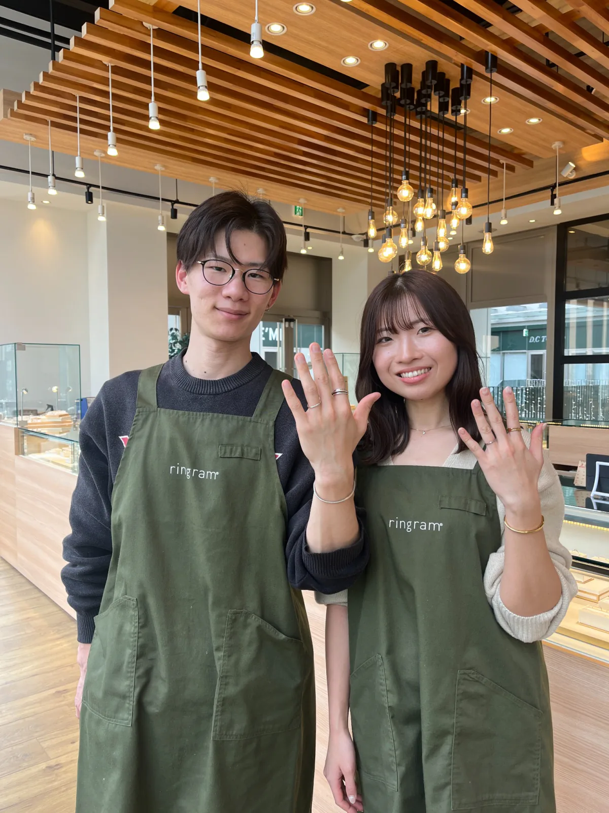 指輪を見せながら並ぶ二人の縦写真